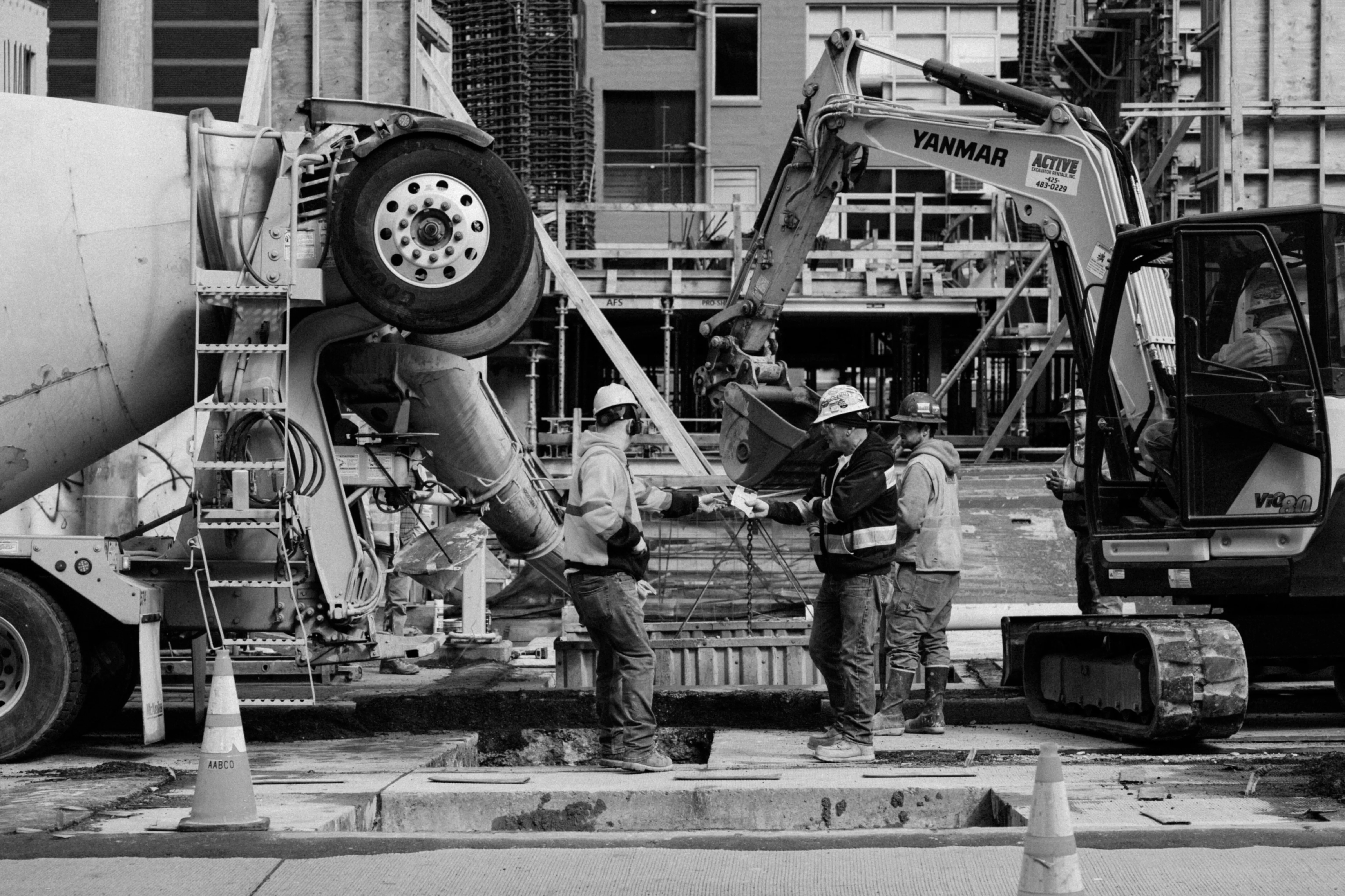 Ouvriers sur un chantier de construction avec bétonnière et pelleteuse